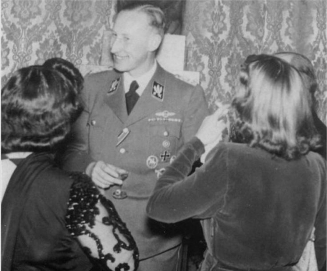 Reinhard Heydrich smiling with a small group of women surrounding him.